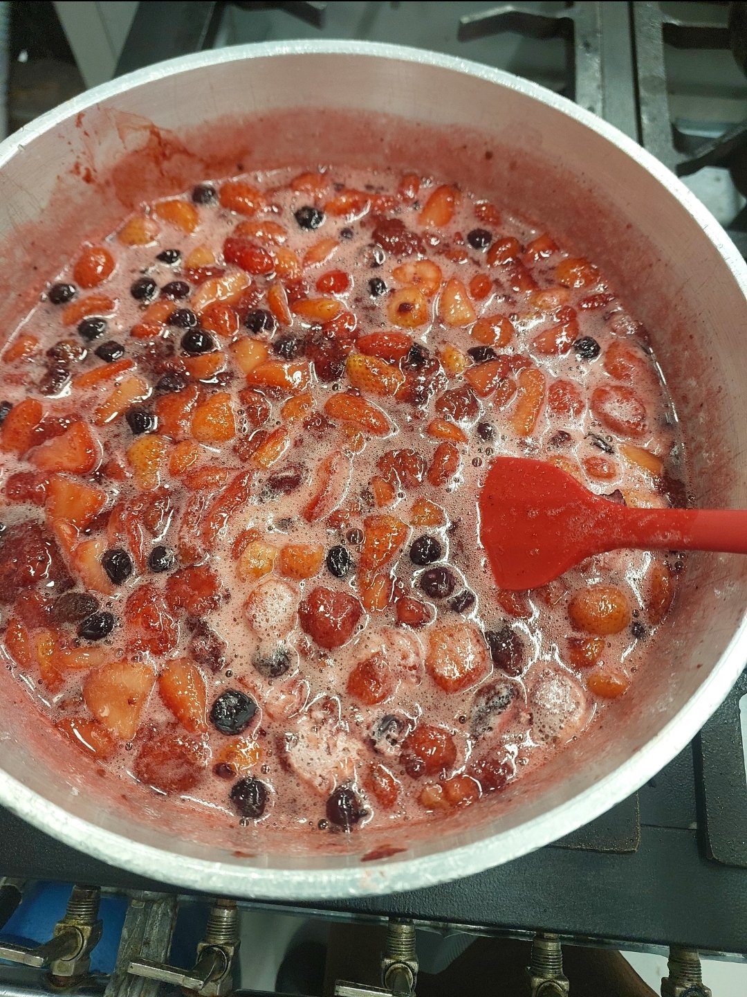 Morangos e frutas vermelhas amolecendo em fogo baixo, ainda inteiros, soltando suco antes de bater