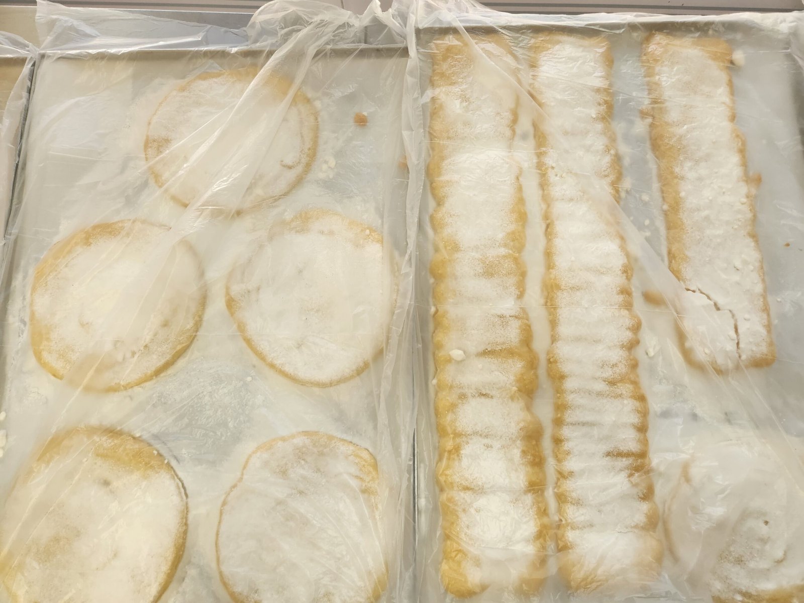 assadeiras de tiras e discos assados cobertas com filme plástico, prontas para estocagem (substituto aproximado: foto de processo do biscuit em `Bases\`, não da parede montada)
