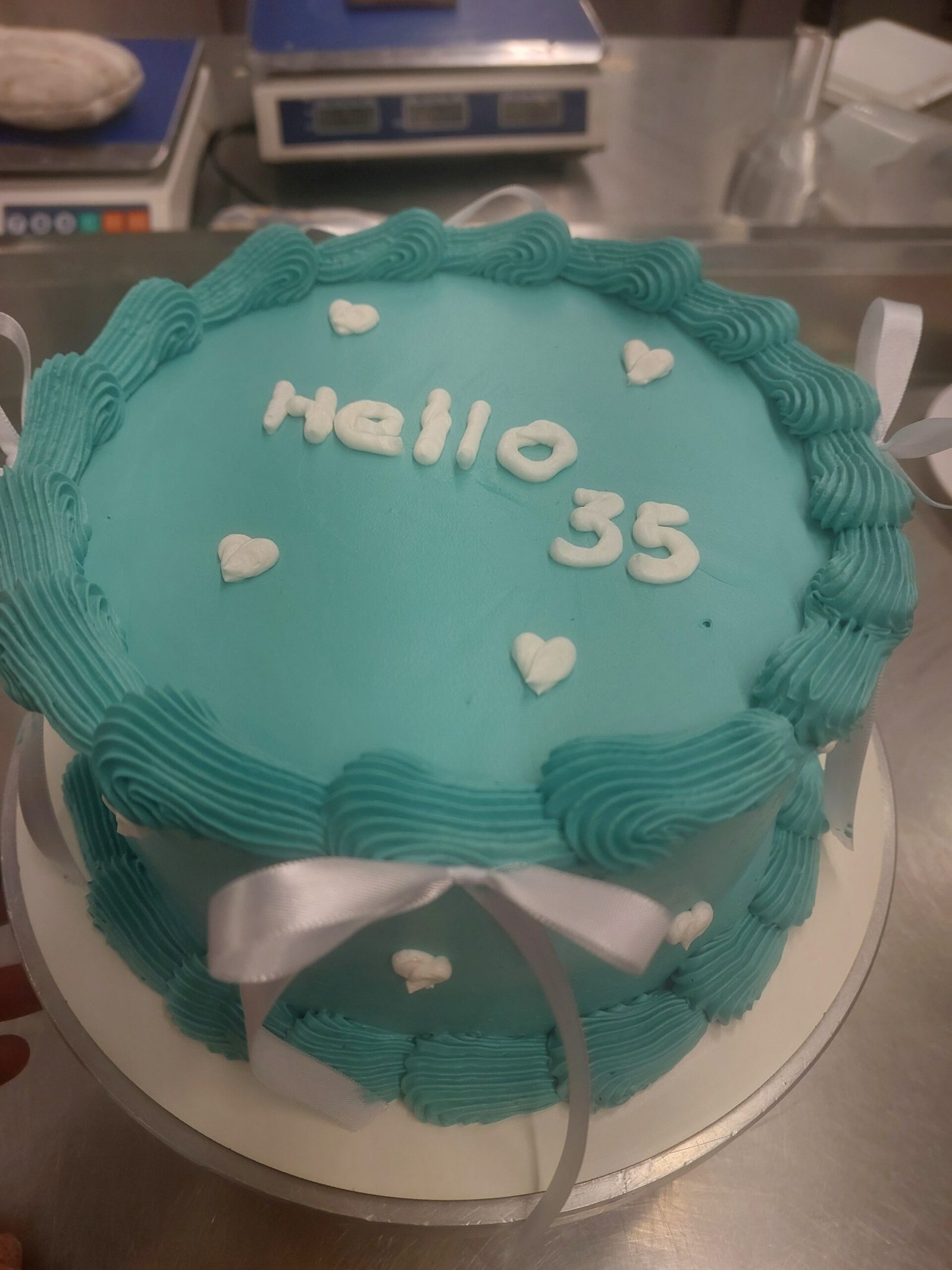 bolo coberto em buttercream azul-claro liso, com borda em piping e letras aplicadas, superfície do topo sem migalha aparente