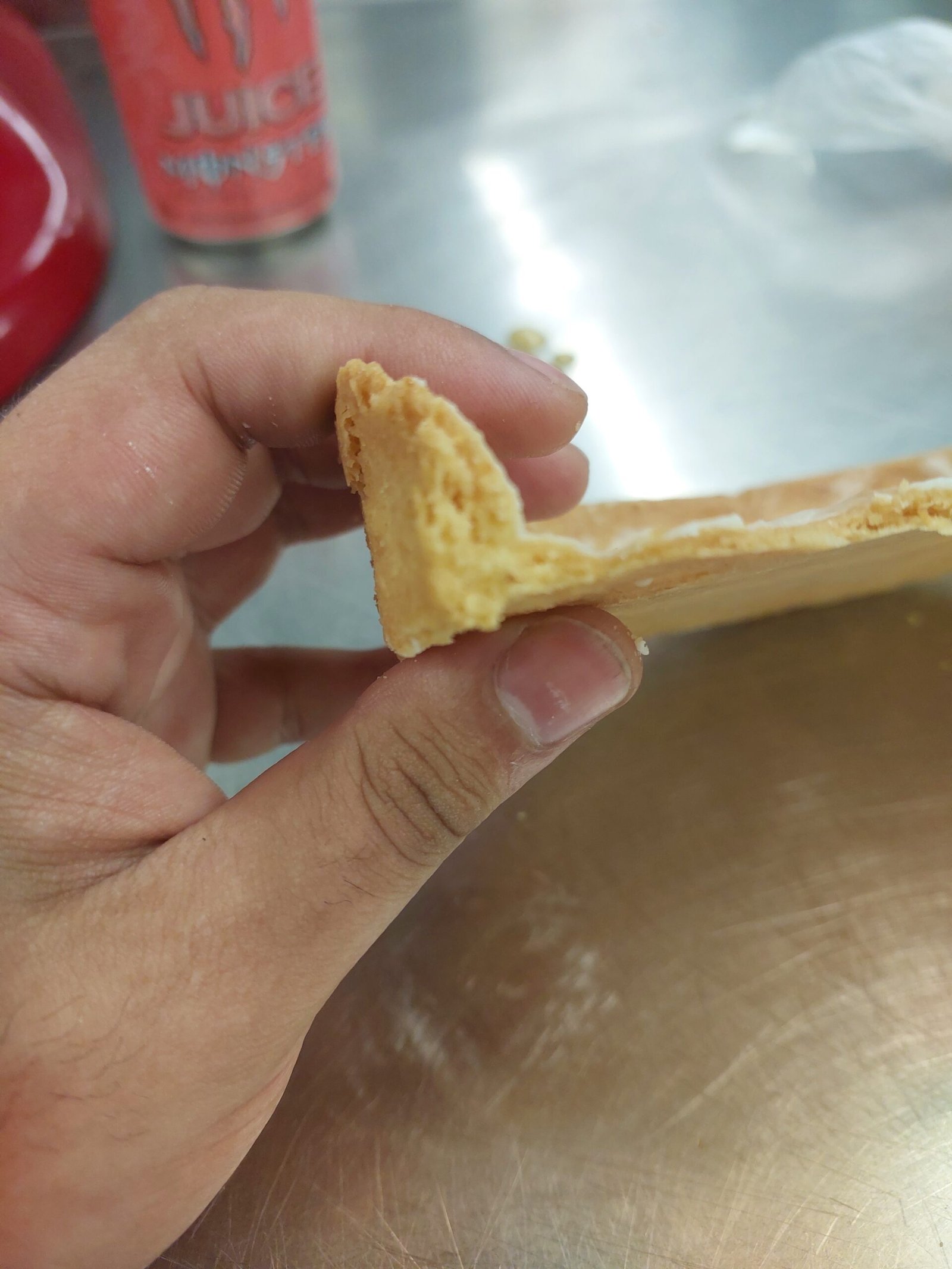 fragmento de parede e fundo de tarte segurado entre os dedos, com a espessura da parede e o canto do fundo visíveis em corte