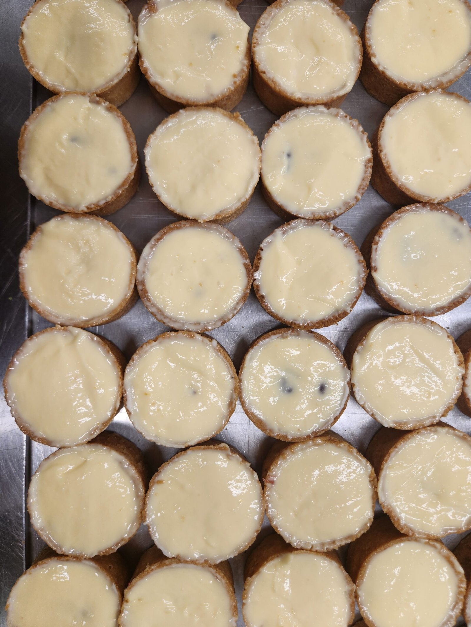 bandeja lotada com dezenas de tarteletes do mesmo lote, todas com a parede de massa assada visível