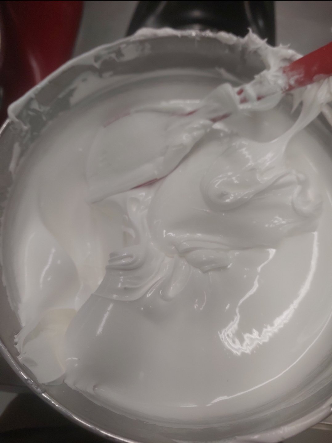 massa branca lisa e brilhante sendo trabalhada com espátula, borda da tigela limpa (substituto aproximado: merengue italiano, não mascarpone)
