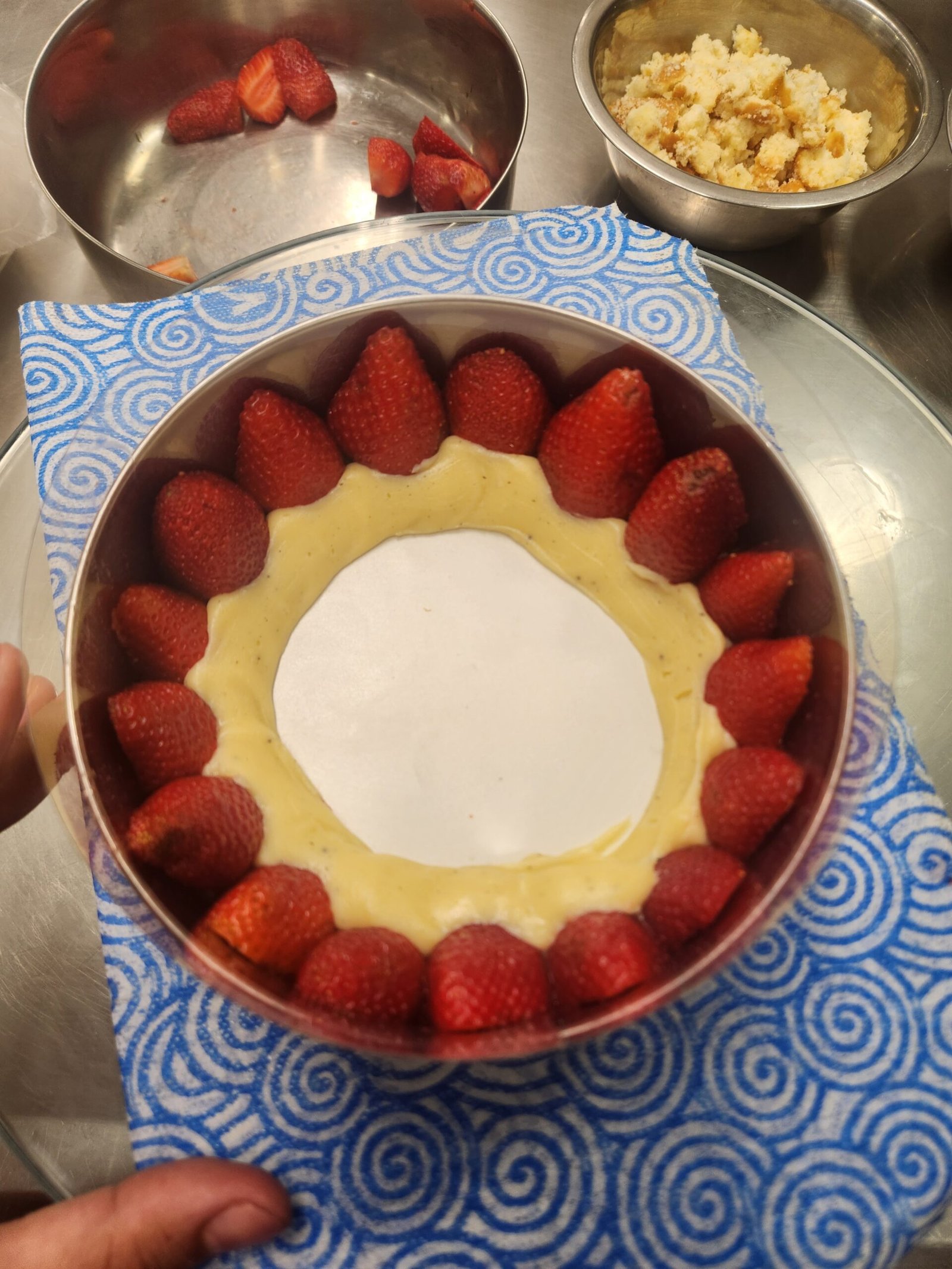 Morangos inteiros de polpa firme em contato direto com o creme durante a montagem de uma peça.