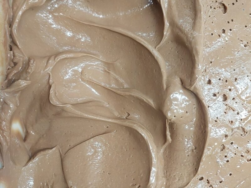 Ganache de chocolate cremosa e brilhante, espalhada em ondas na assadeira, no ponto de rechear