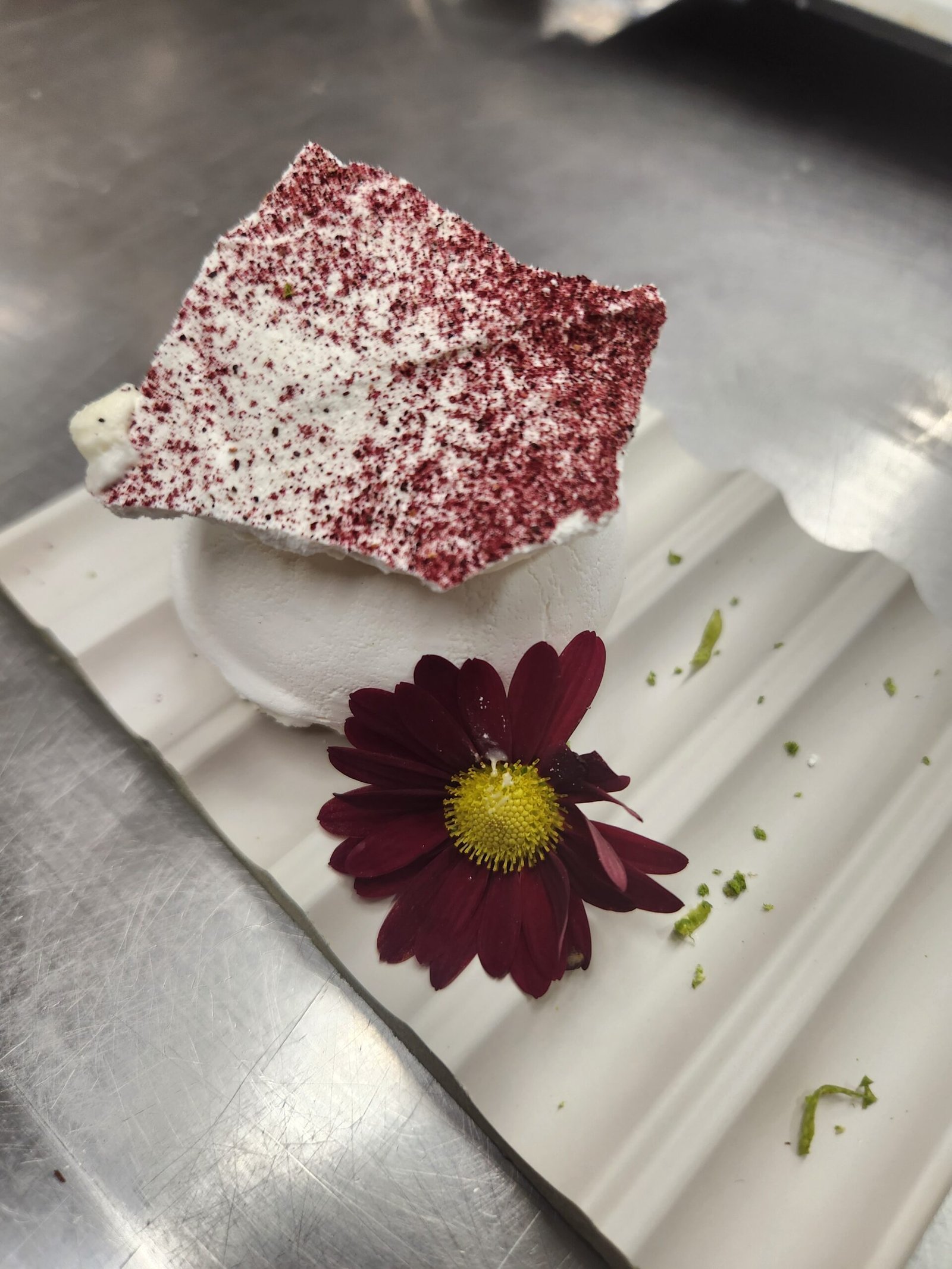 Pavlova assada com casca branca e opaca, sem dourar, finalizada com lâmina de merengue e pó de frutas vermelhas