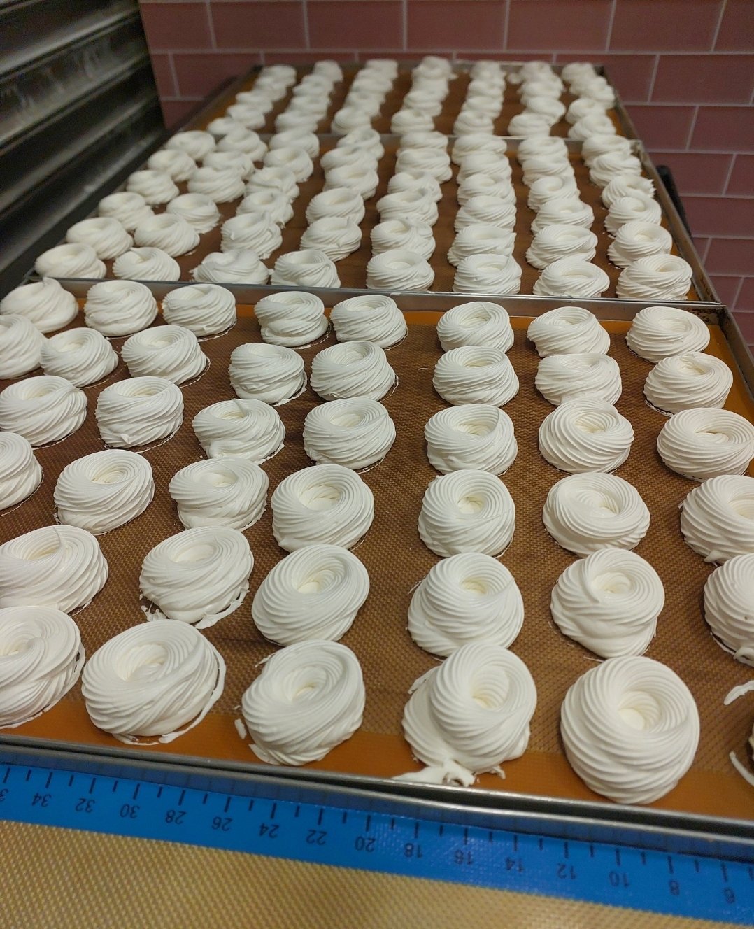 Minipavlovas modeladas no tapete de silicone antes do forno: espuma firme que mantém o desenho do bico