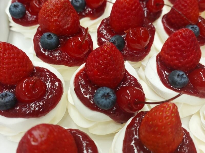 Minipavlovas montadas com chantilly, coulis de frutas vermelhas, morango, mirtilo e cereja: a cobertura úmida entra na hora de servir