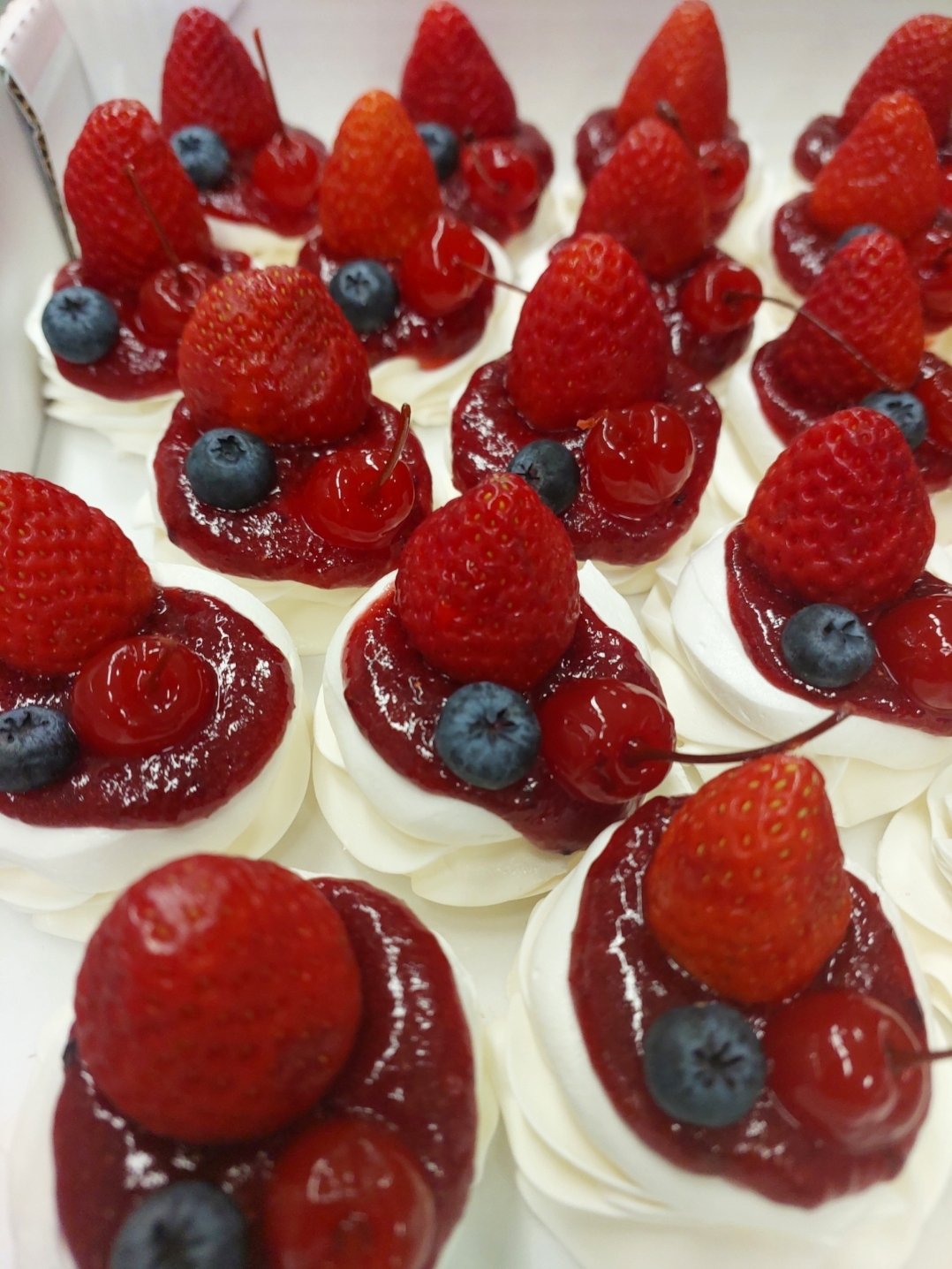 Minipavlovas montadas com chantilly, coulis de frutas vermelhas, morango, mirtilo e cereja: a cobertura úmida entra na hora de servir